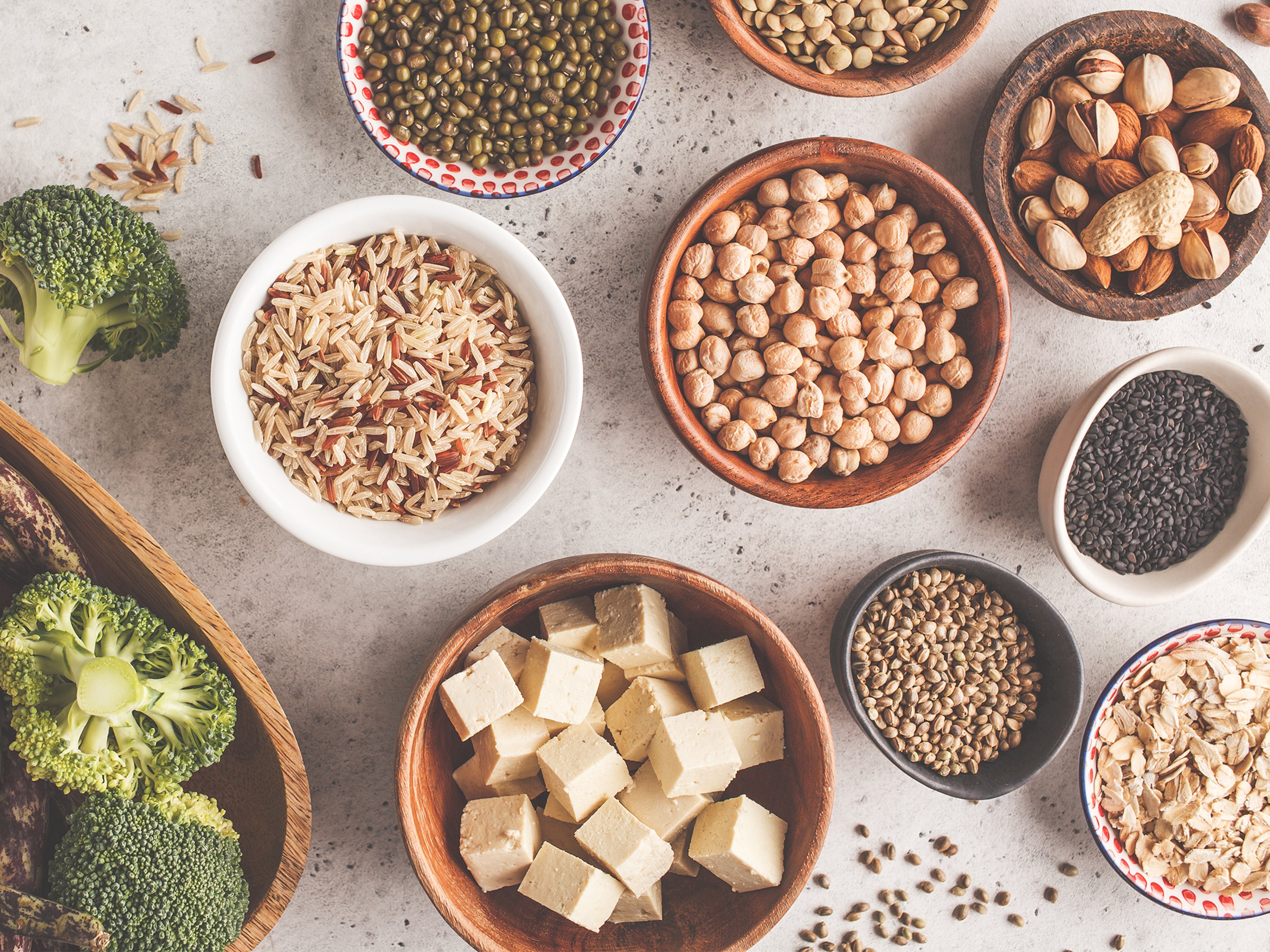 Flat lay of bowls of ingredients such as dried lentils, dried chickpeas and cubed firm tofu.