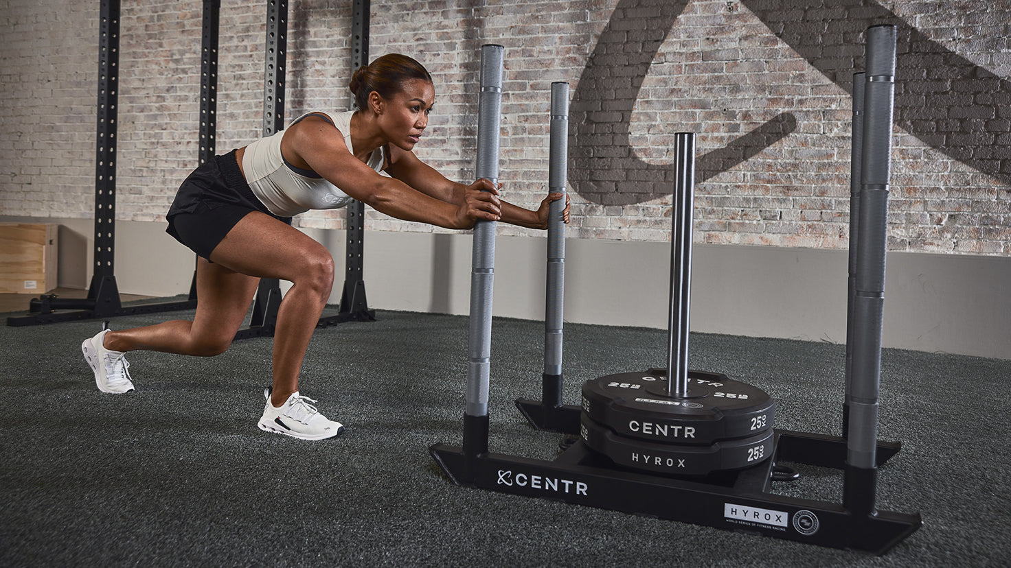 Centr Trainer Maricris Lapaix pushes a Centr-branded Hyrox sled.