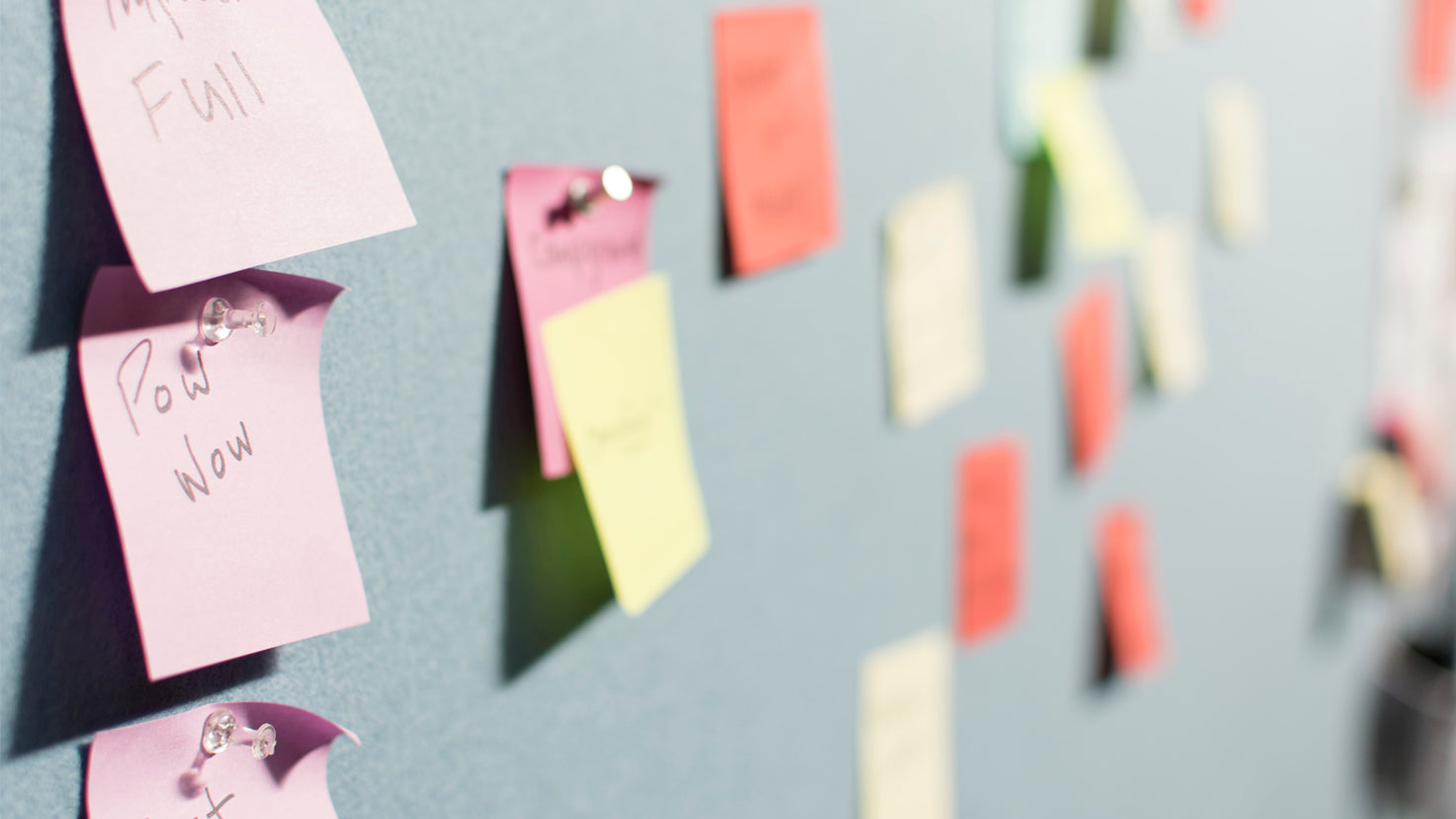 Dozens of different colored Post-it notes on a bulletin board.