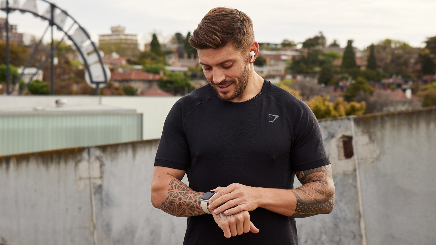 Centr trainer Luke Zocchi, wearing black workout clothing, checks his smart watch during a training