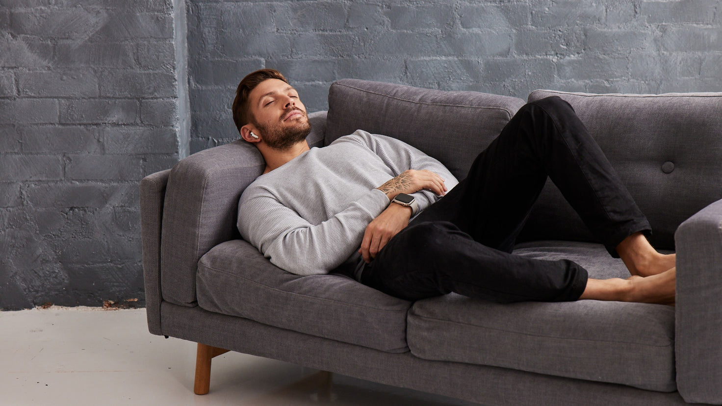 Luke Zocchi reclines on a couch with his eyes closed, ear pods in his ears.