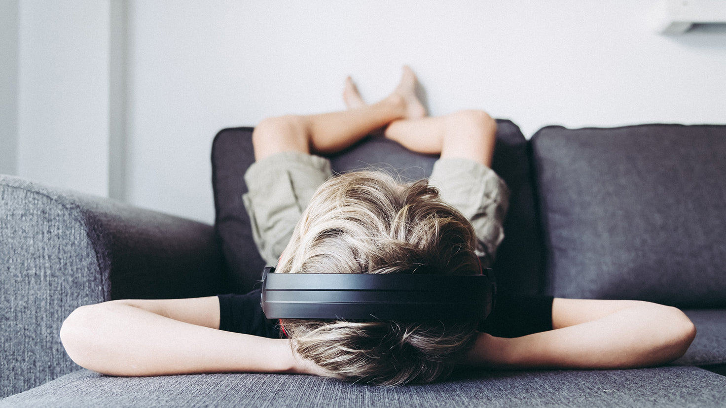 A young boy relaxes on the couch while listening to a Centr meditation.