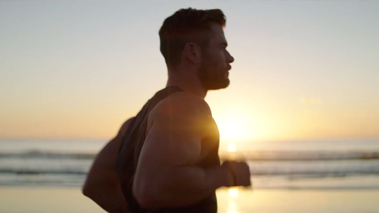A video still of Chris Hemsworth running on the beach.
