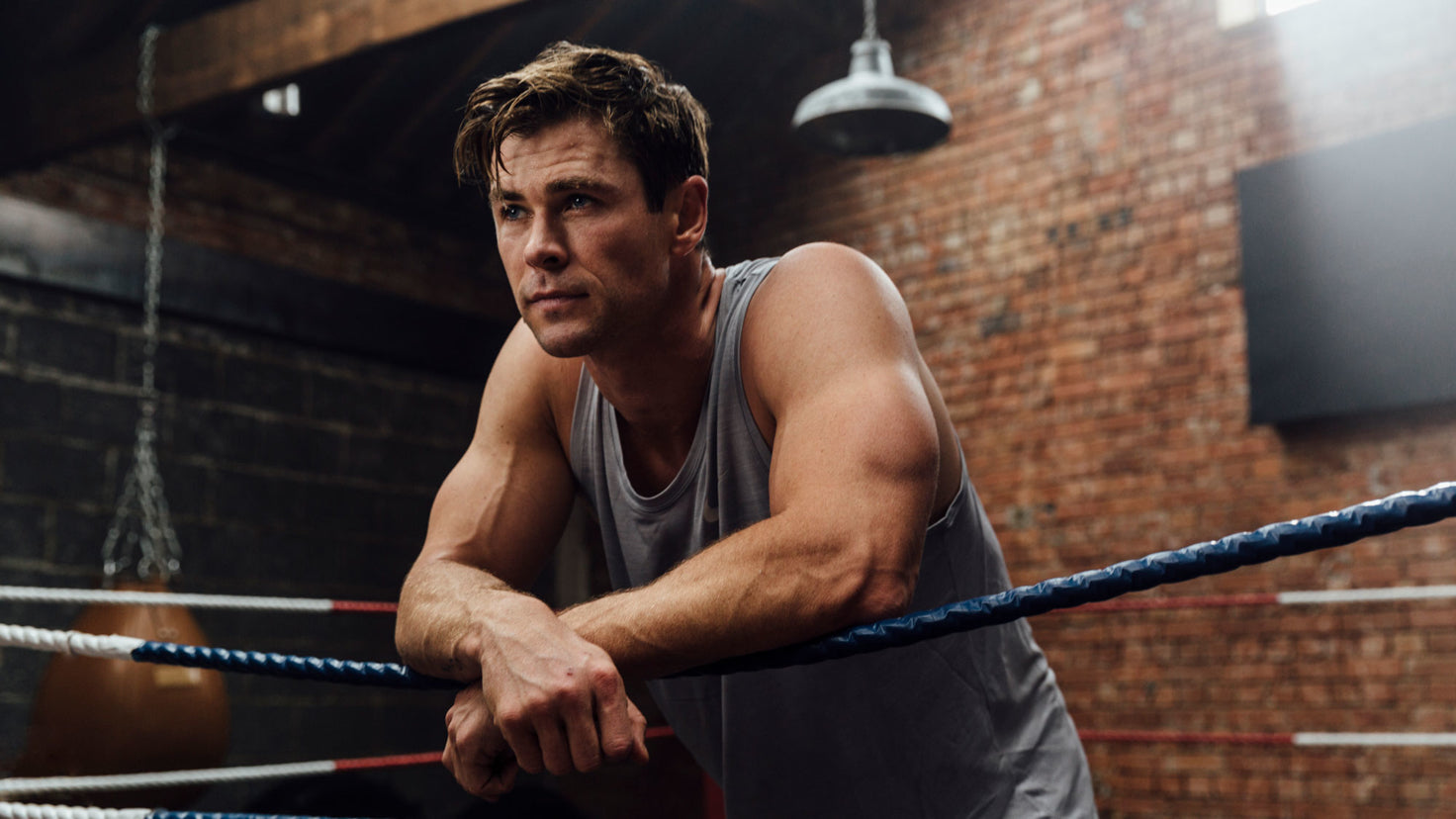 Chris Hemsworth leans against the ropes of a boxing ring.