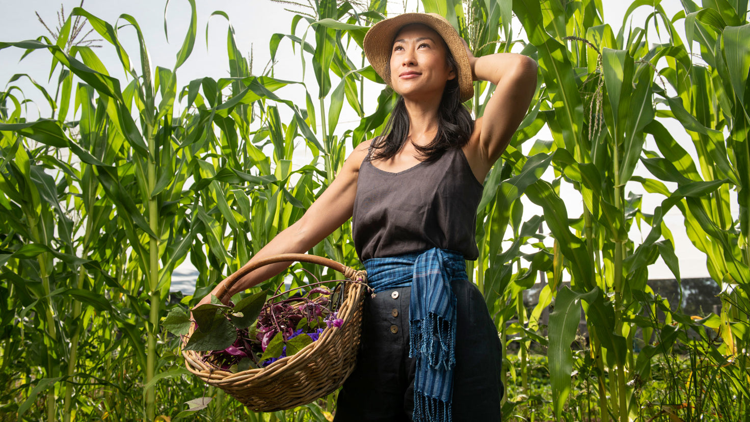 Palisa Anderson standing in a field surrounded by tall green plants.