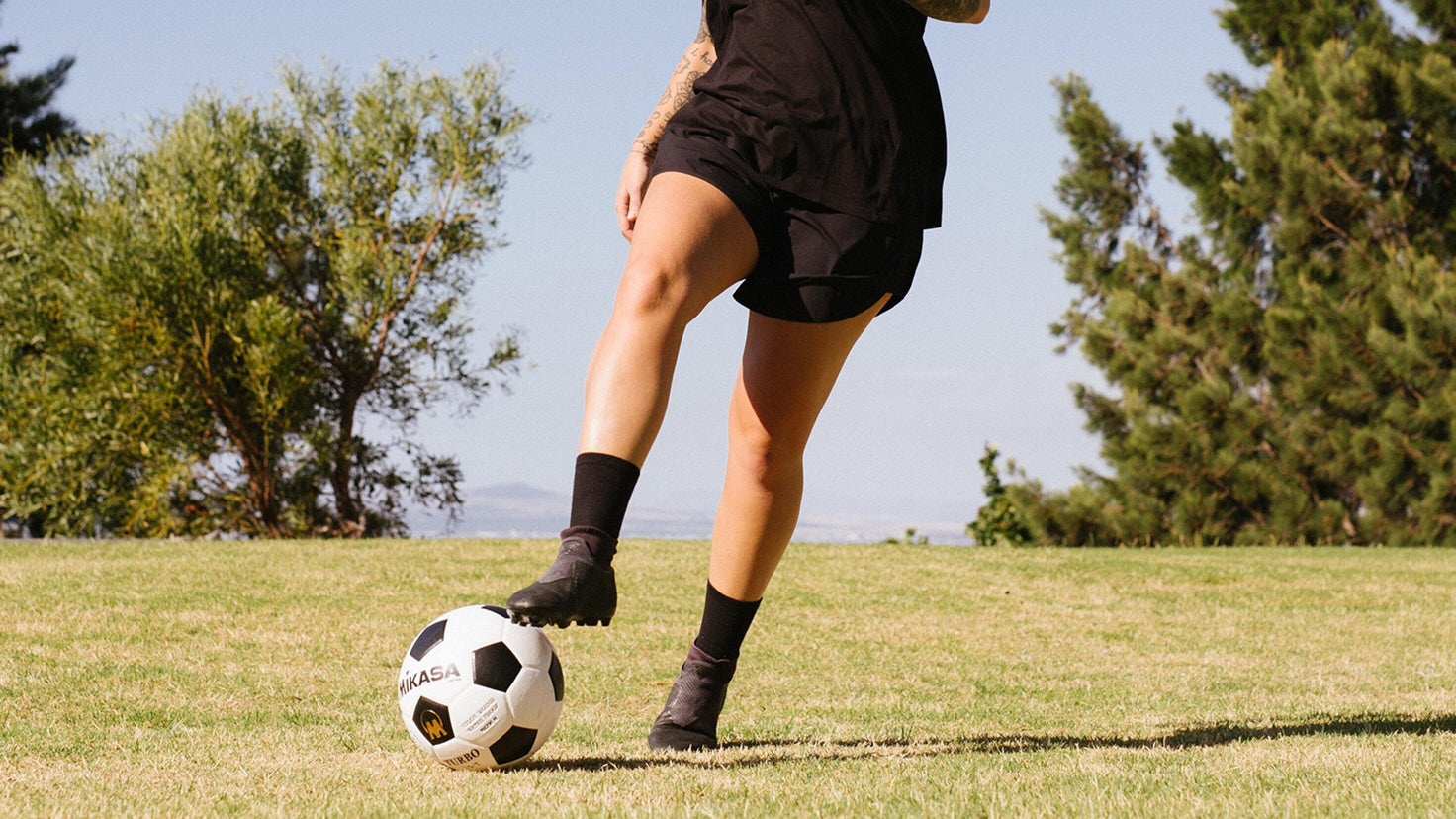 An image of the legs of 2 soccer players midaction, vying for control of a soccer ball.