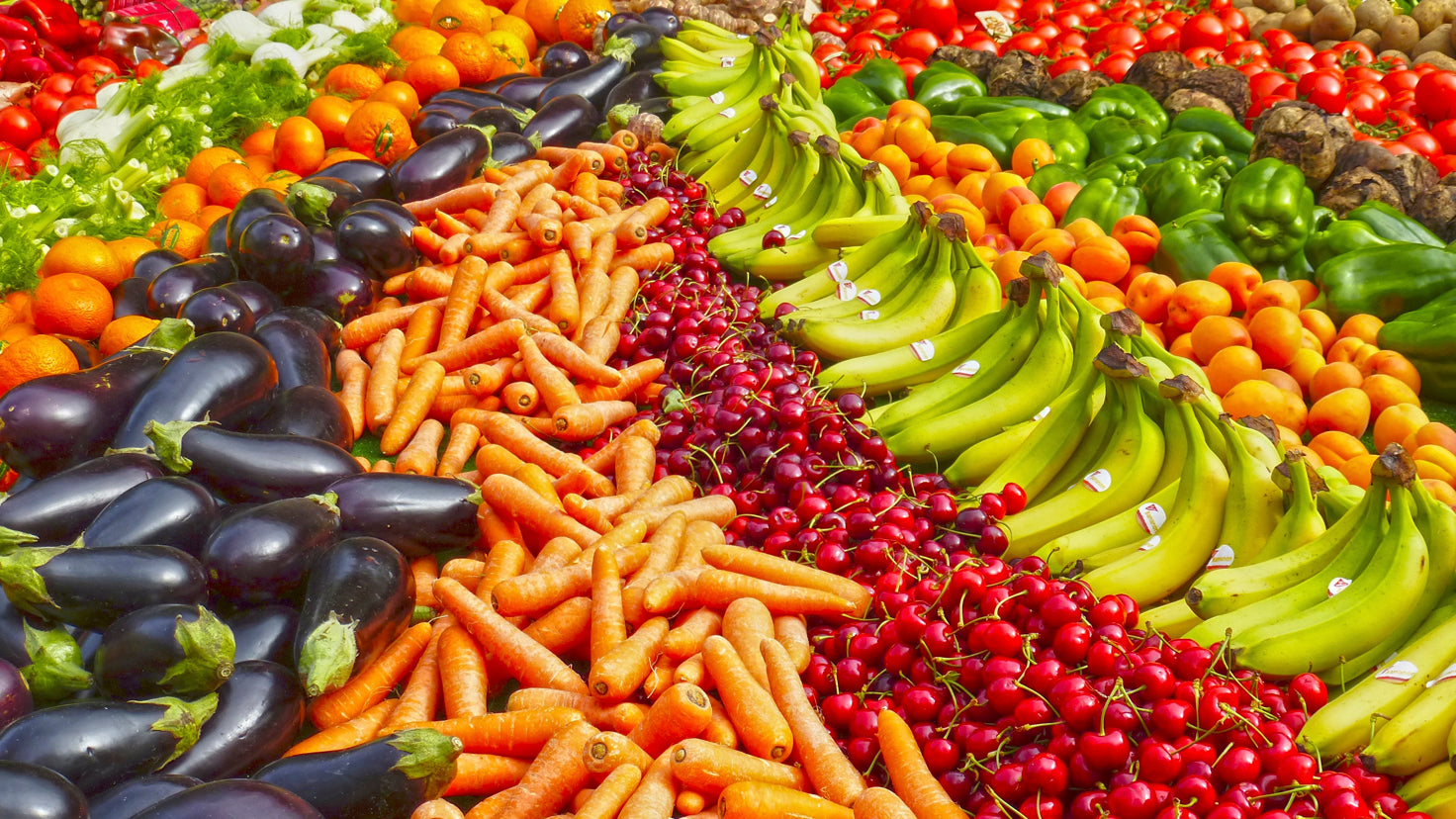 Rows and rows of colorful fruits and vegetables, including carrots, cherries, bananas and eggplants.