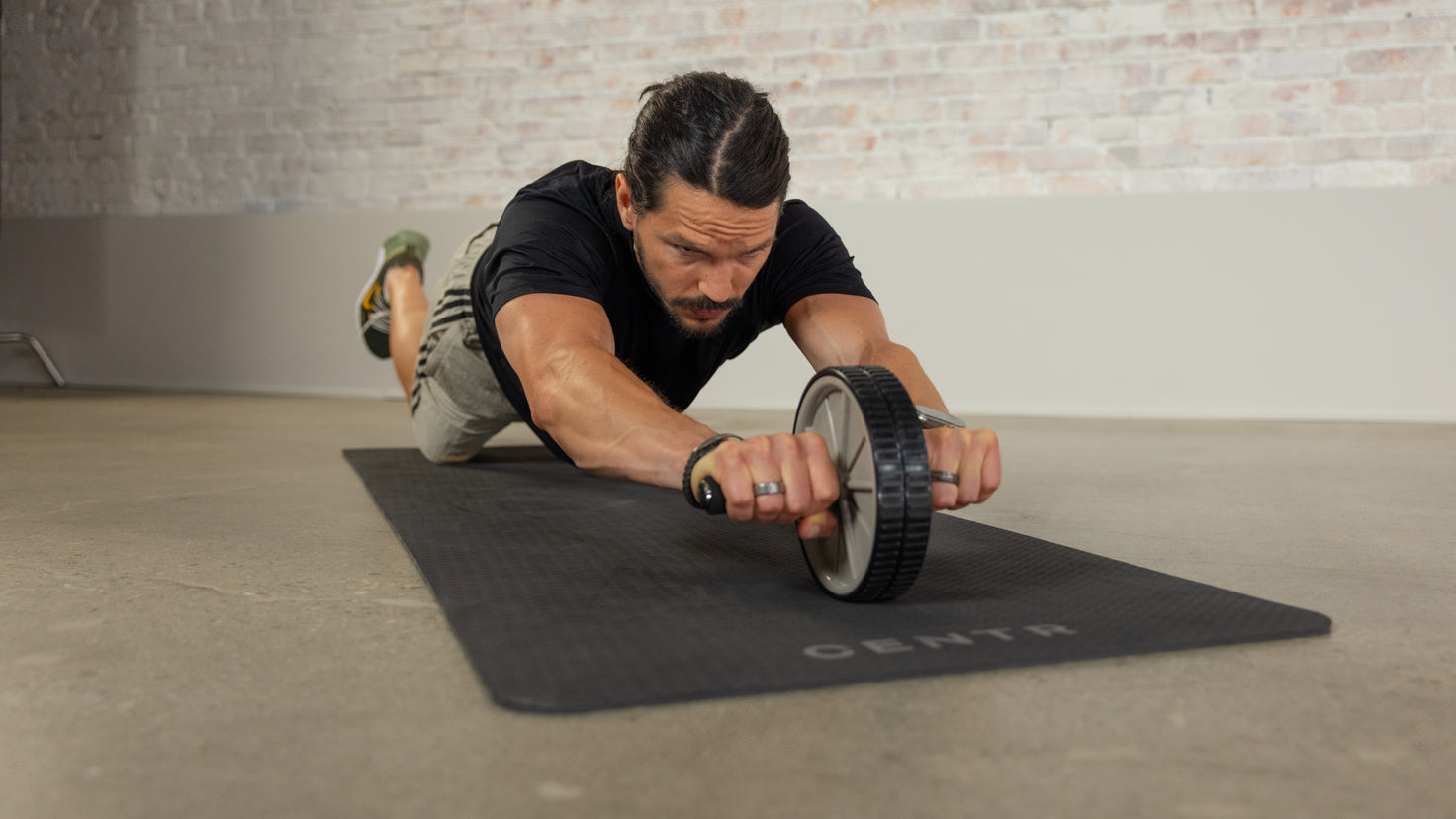 A head-on photo of Centr trainer Dan Churchill rolling out his ab roller towards the camera.