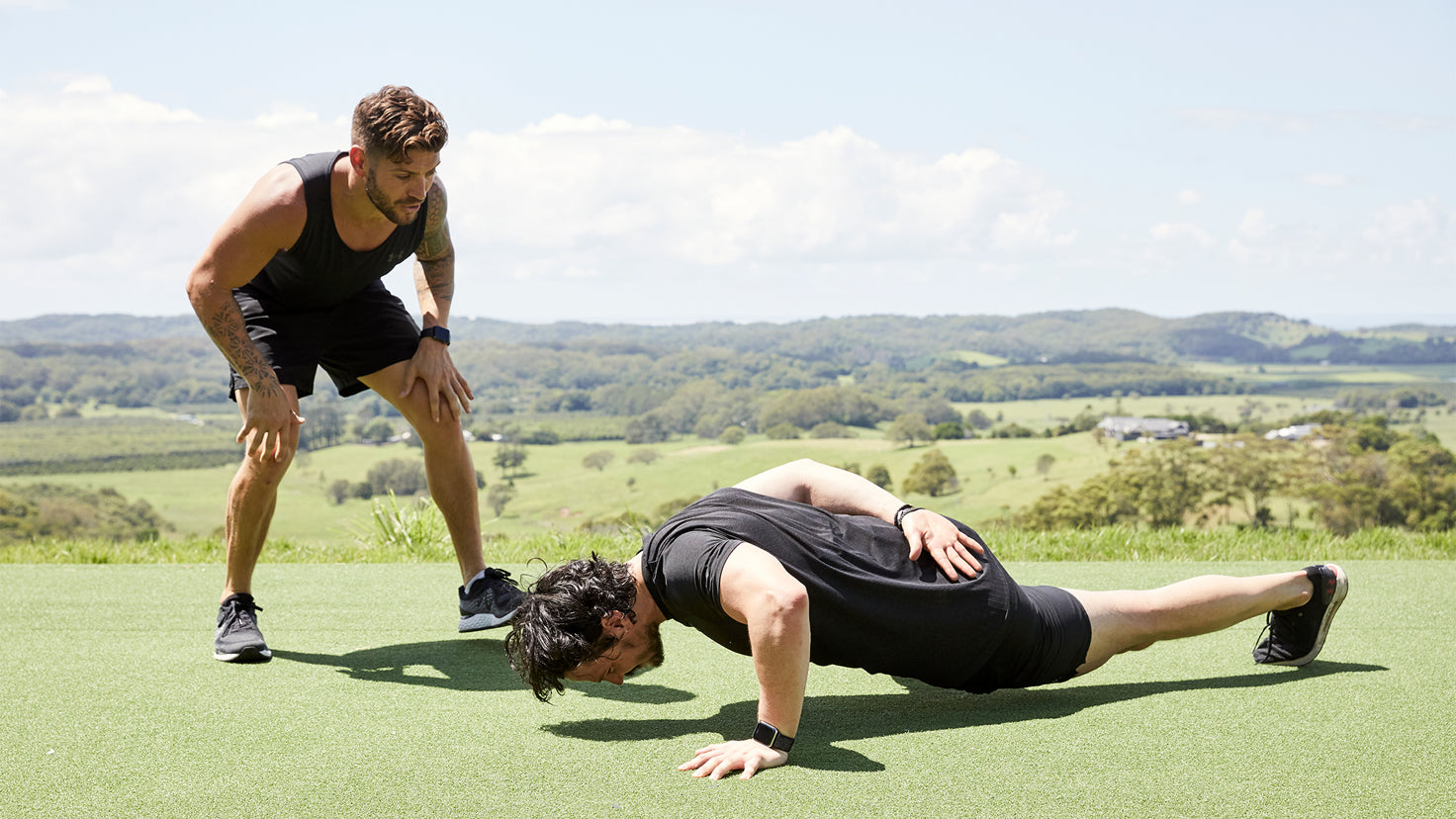 Luke Zocchi watches Dan Churchill while Dan does a one-armed push-up.