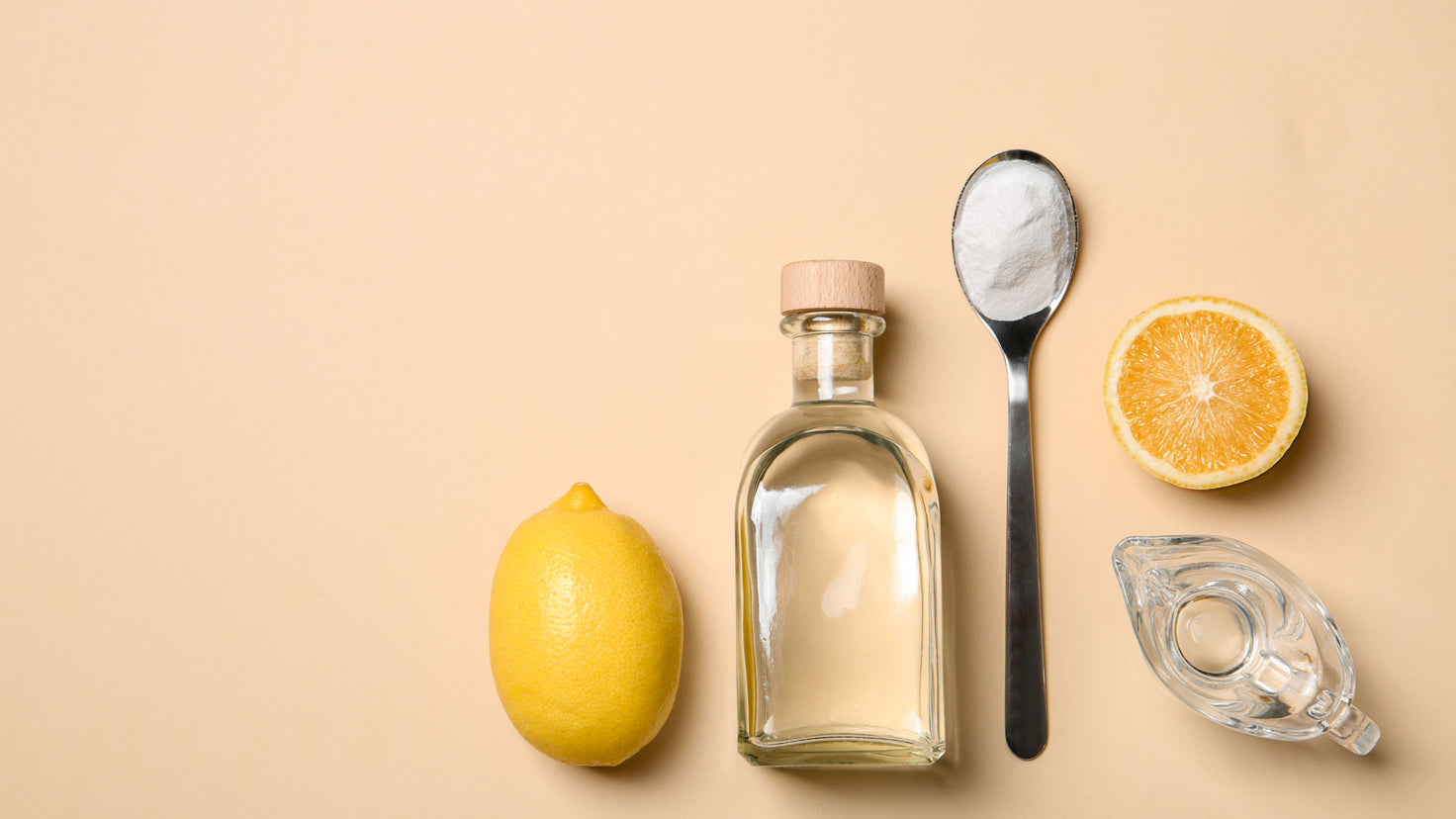A lemon, a glass bottle, a spoon of baking soda and a small glass of vinegar.