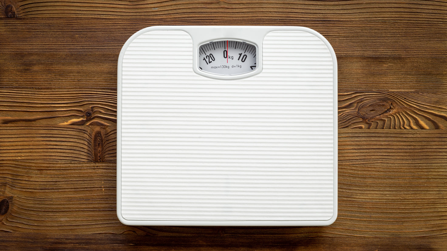 Two grey-socked feet stand on a set of bathroom scales.