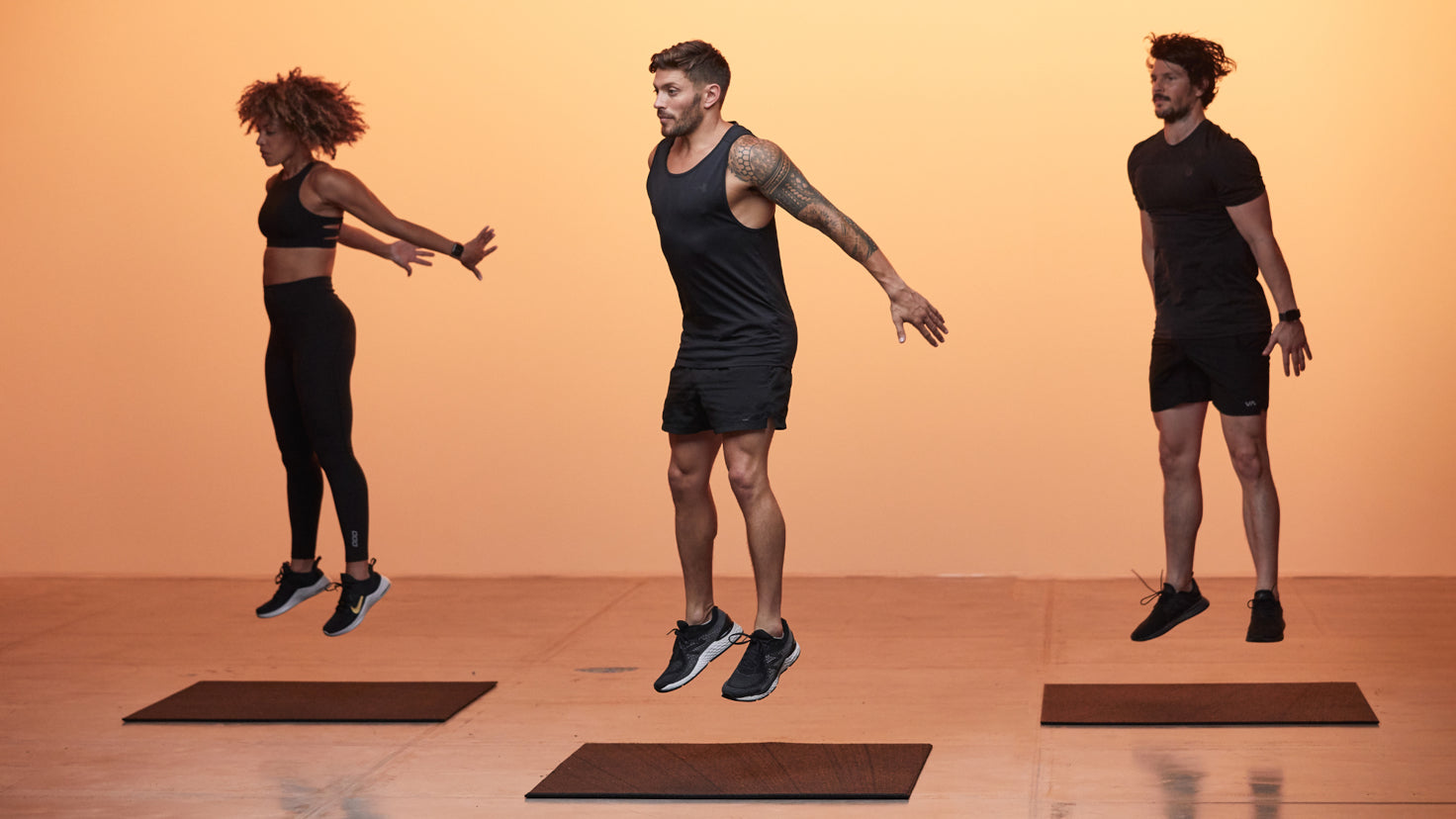 Three people are mid-jump in an exercise routine.