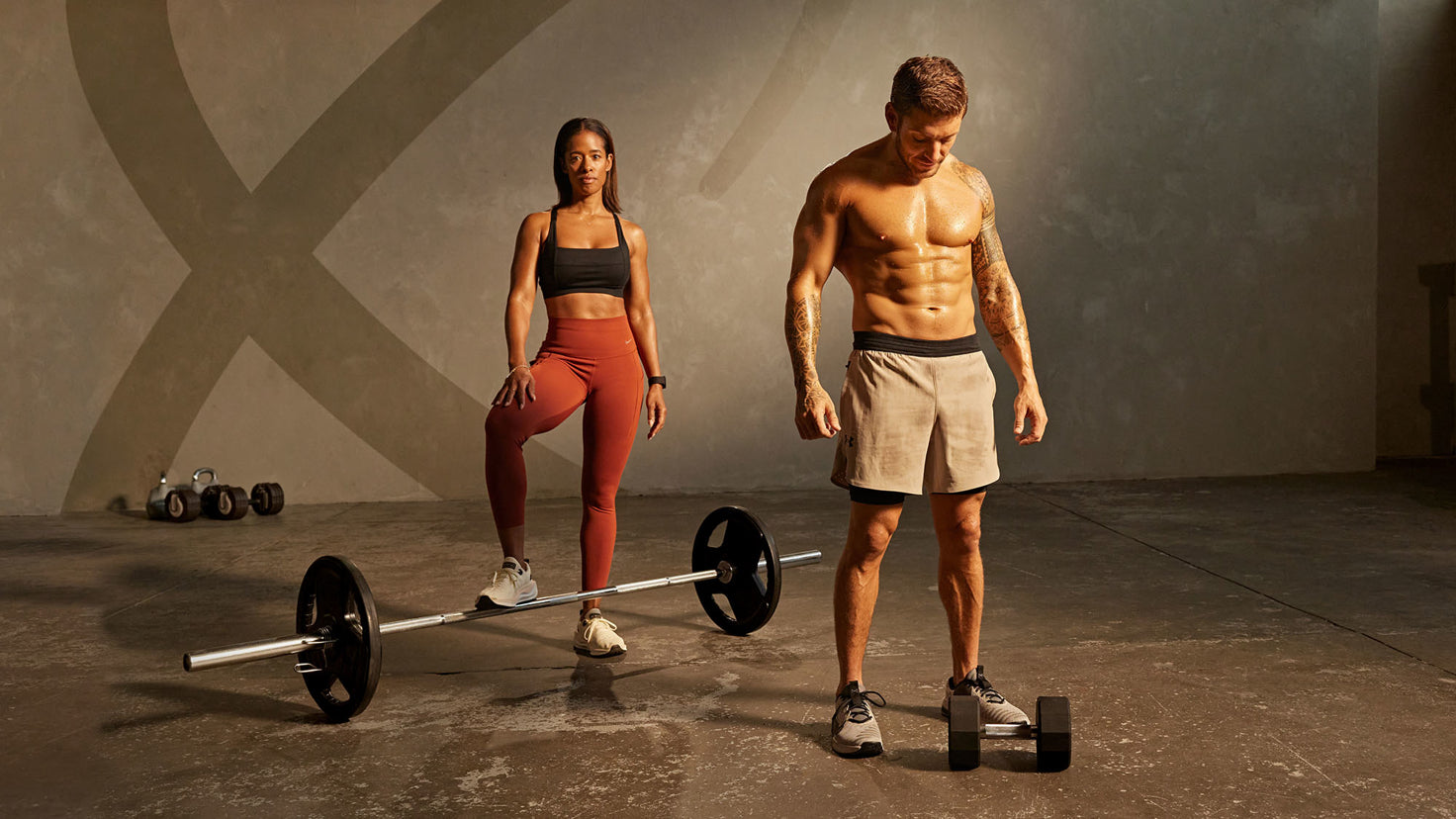 Centr trainers Luke Zocchi and Ingrid Clay stand with a barbell and a set of dumbbells.