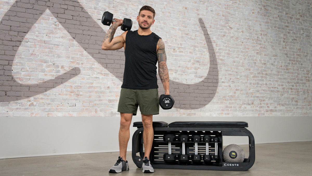 Centr trainer Luke Zocchi stands holding two dumbbells.