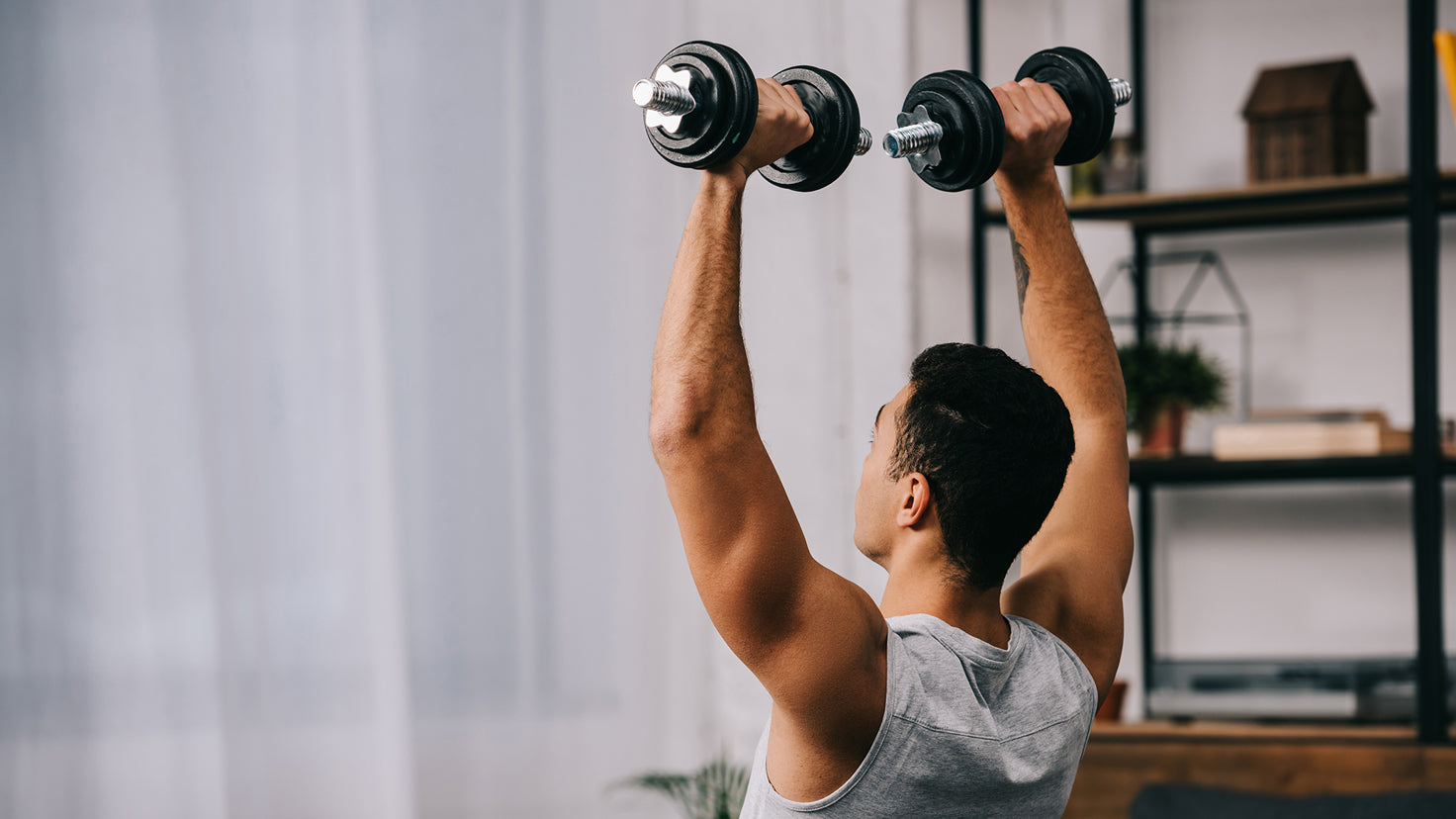 A man lifts dumbbells at home.