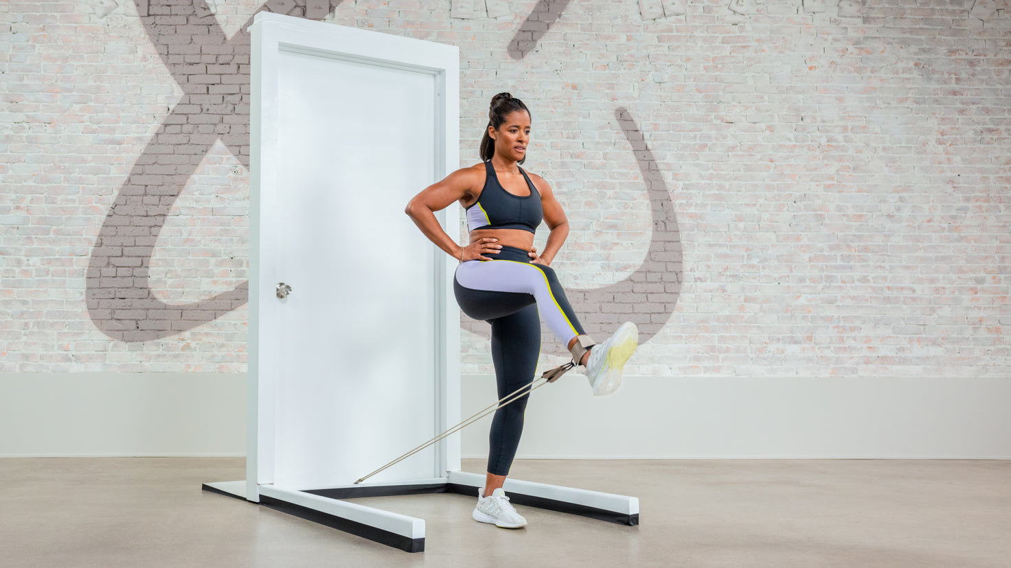Ingrid Clay uses a Centr tube band to perform a leg strengthening exercise, using a door frame as an