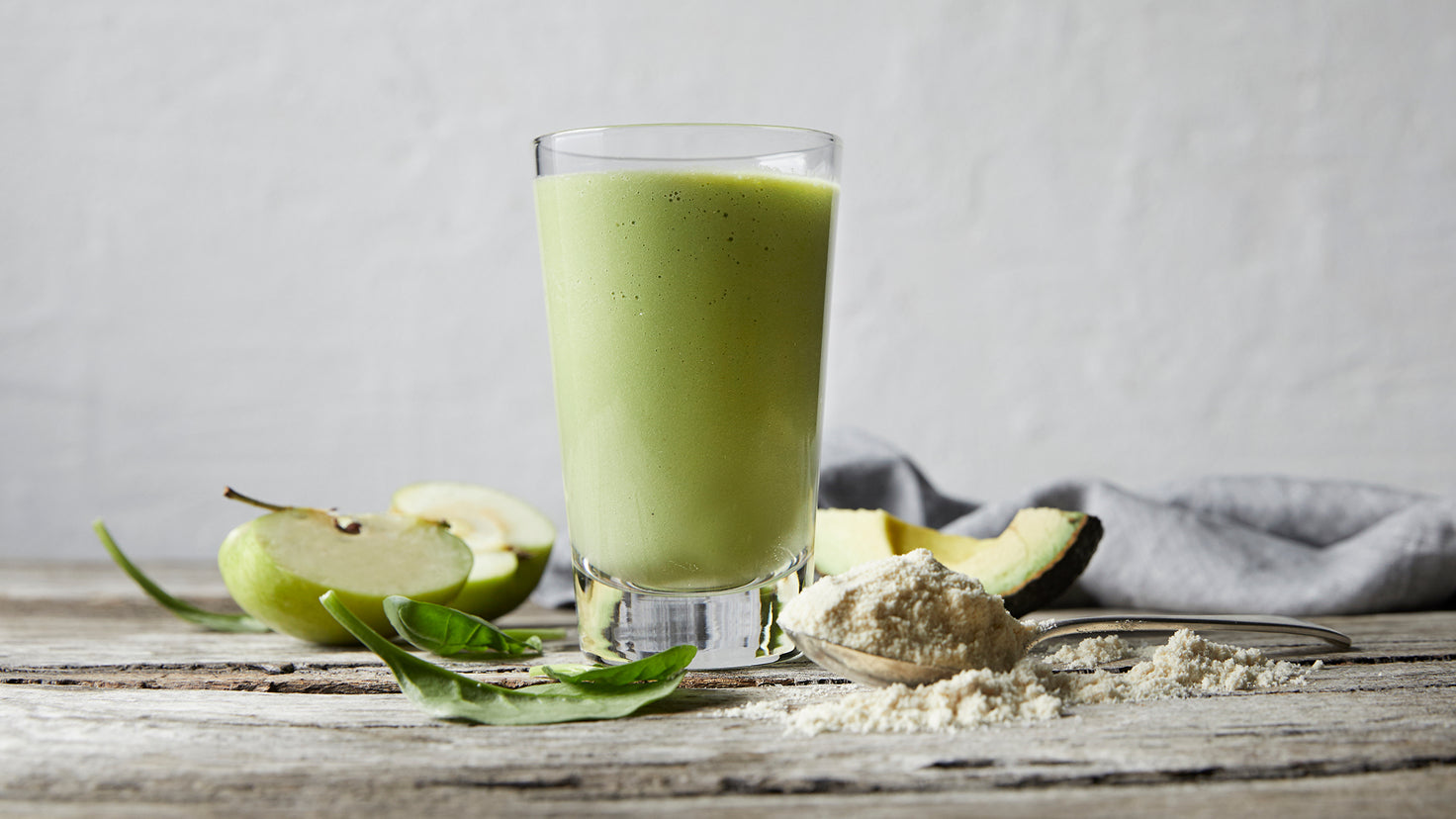 A green super smoothie from the Centr meal plan, surrounded by chopped apple and avocado.
