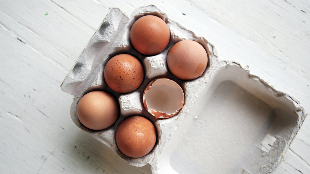 A carton containing five eggs and one eggshell.