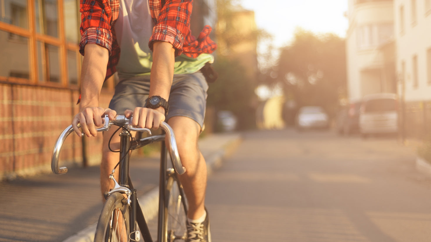 A man riding a bike on a sunny day, shown from the neck down.