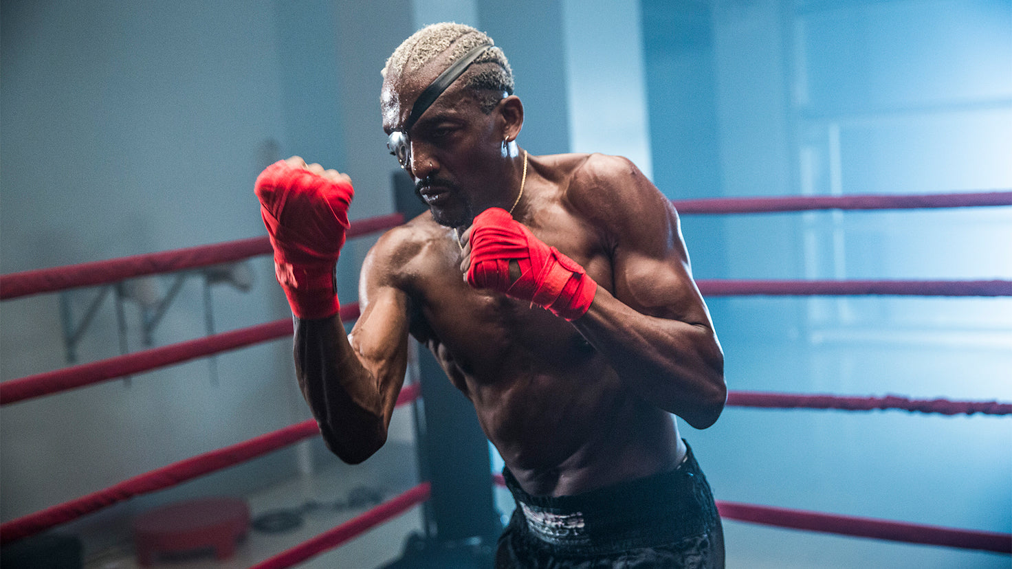 Michael Olajide Jr. (wearing red hand wraps) practices punches in a boxing ring.