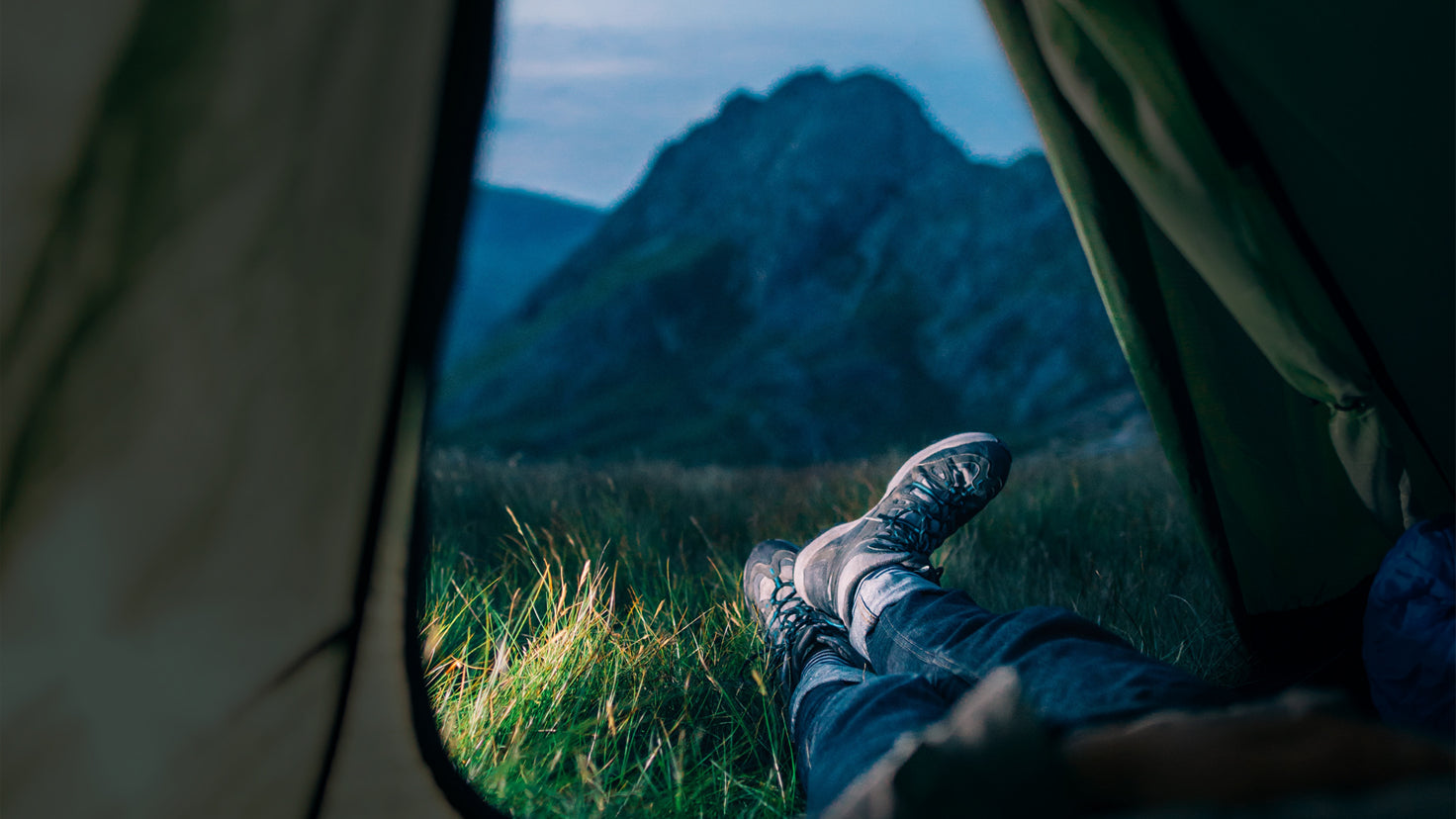 A person lays in a tent in the wilderness.