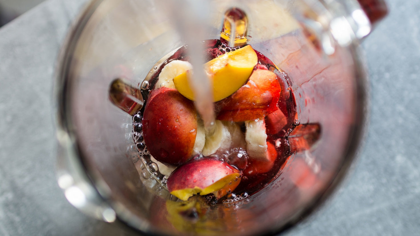 A glass blender filled with peaches and banana.