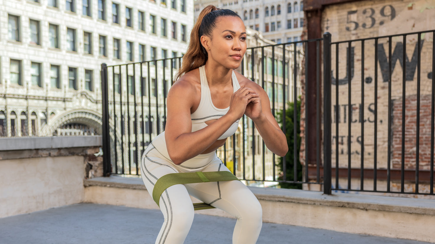 Centr trainer Maricris Lapaix performs a squat exercise using a fabric resistance band whilst workin