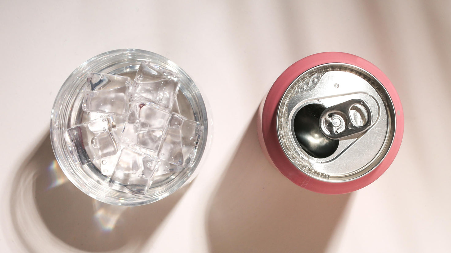 A glass filled with ice and an open can of nootropic drink sit on a table.