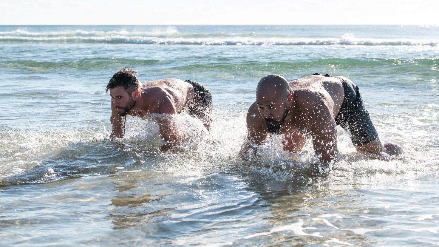 Chris Hemsworth and Joseph Sakoda do bear crawls in the ocean.
