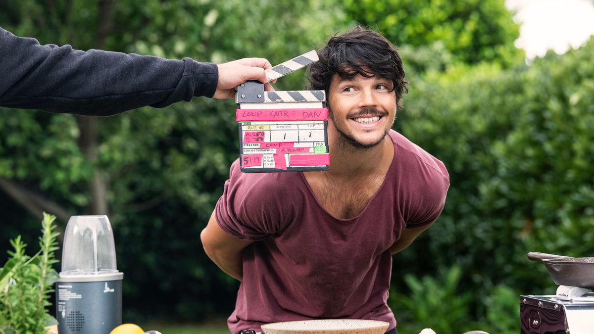 Dan Churchill smiling next to a clapperboard.
