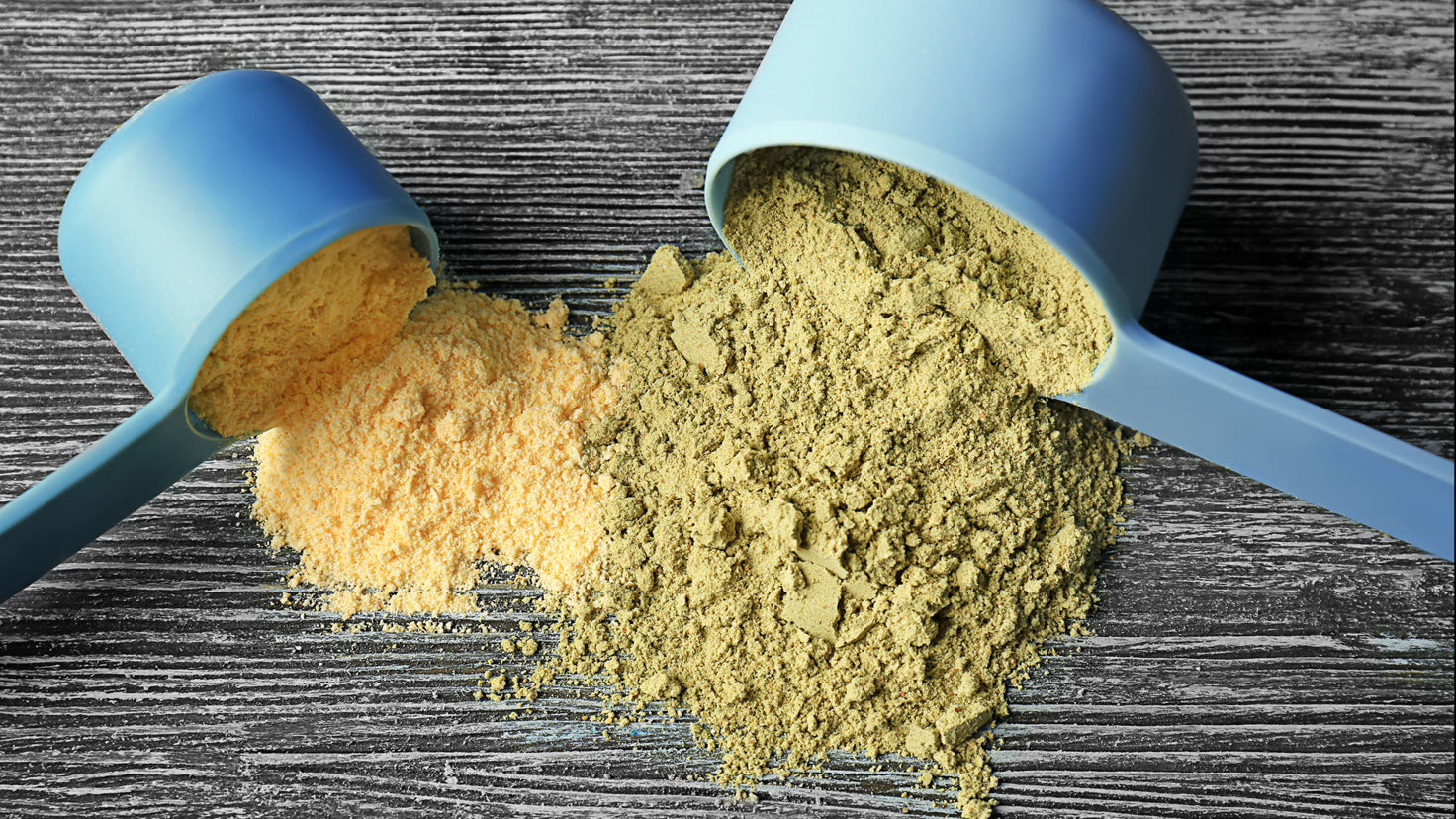 Yellow and green protein powder spilling from two different scoopers.